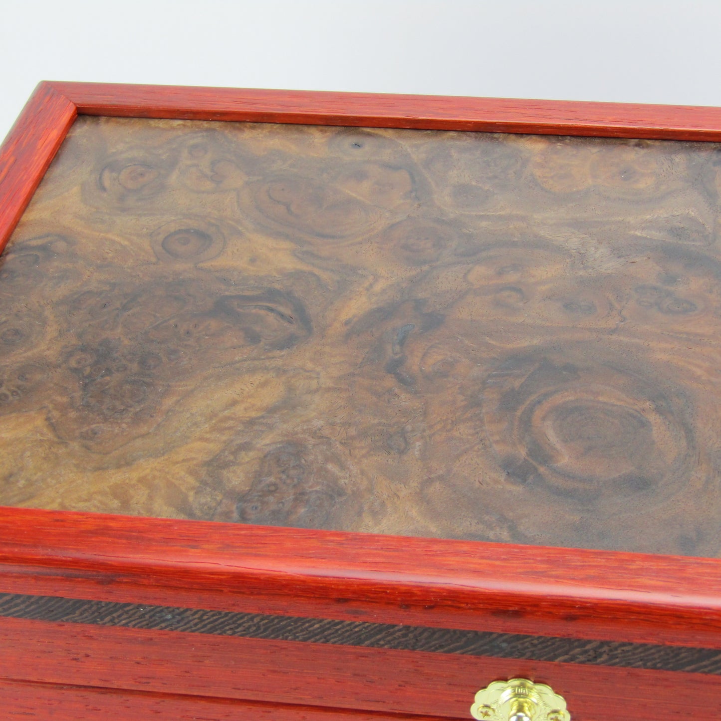 Lid details on handmade wooden box crafted from padauk, wenge, Brazilian cherry, and walnut burl veneer by A Finer Cut Woodworking.