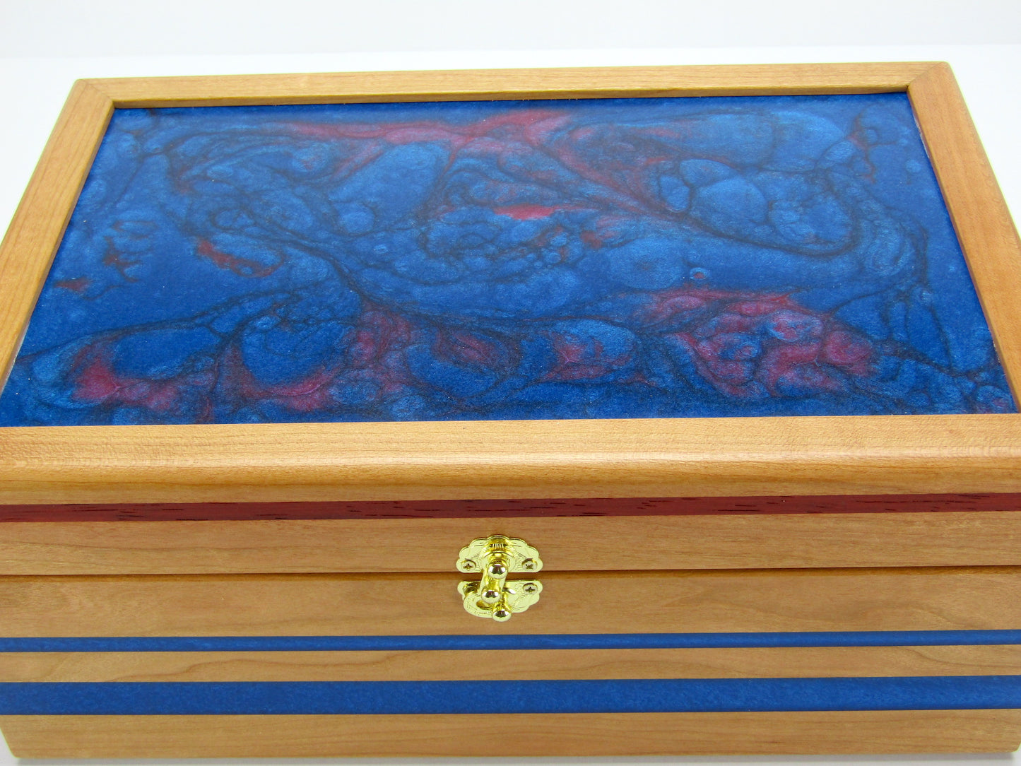 Lid details on keepsake memory box handmade from cherry wood with padauk and epoxy inlays by A Finer Cut Woodwork.