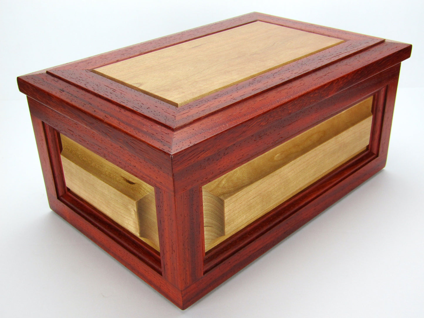 Corner view of large keepsake box with raised panels handcrafted from padauk and cherry wood by A Finer Cut.