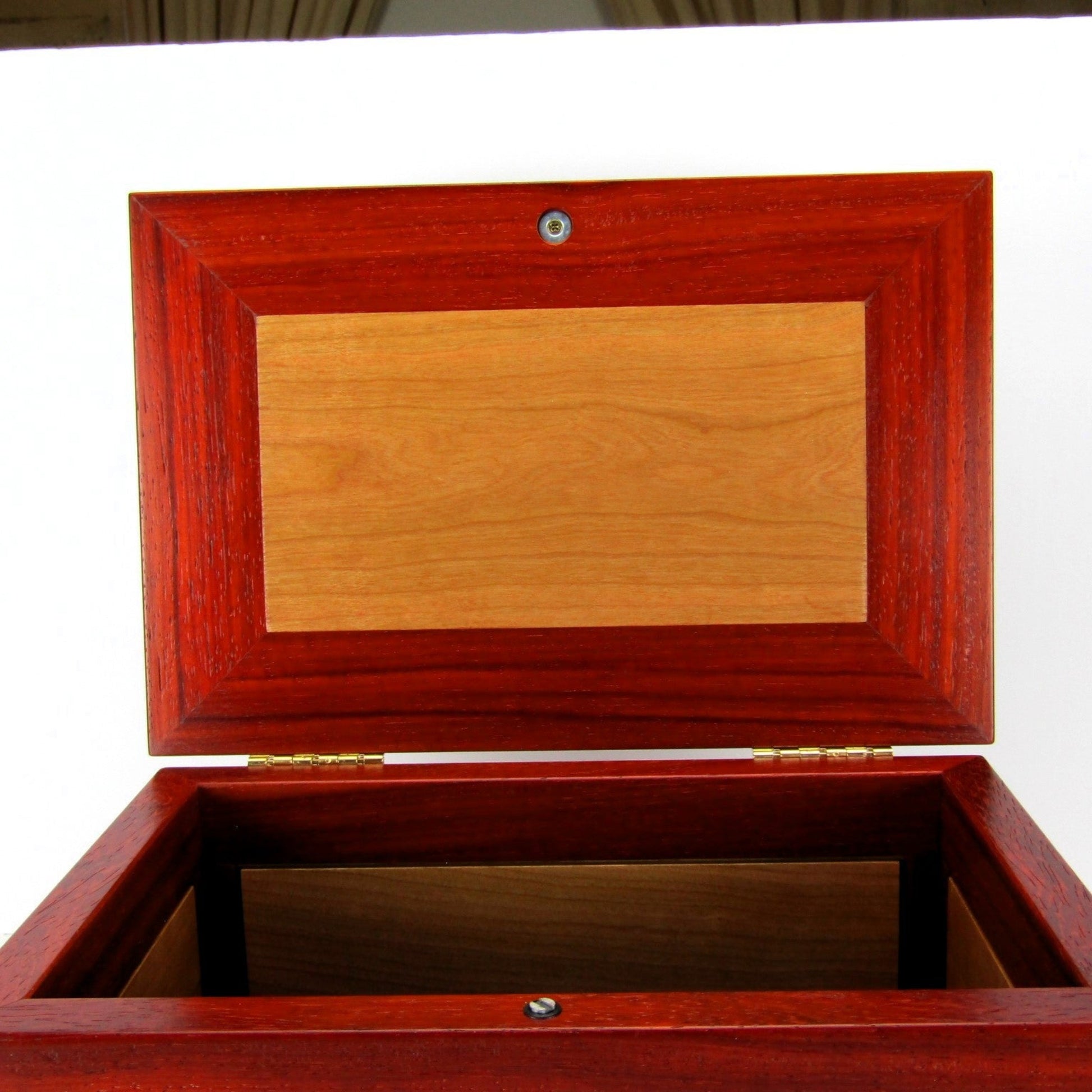 Interior lid of large keepsake box with raised panels handcrafted from padauk and cherry wood by A Finer Cut.