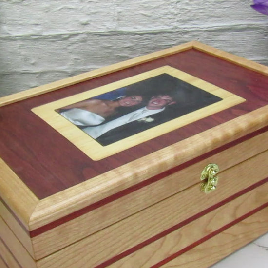 Video showing details of memory box with photo lid handcrafted from cherry, padauk, and dark finished cherry veneer by A Finer Cut Woodworking. 